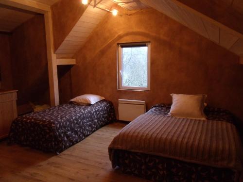 deux lits dans une petite pièce avec une fenêtre dans l'établissement la roseraie, à Fréland
