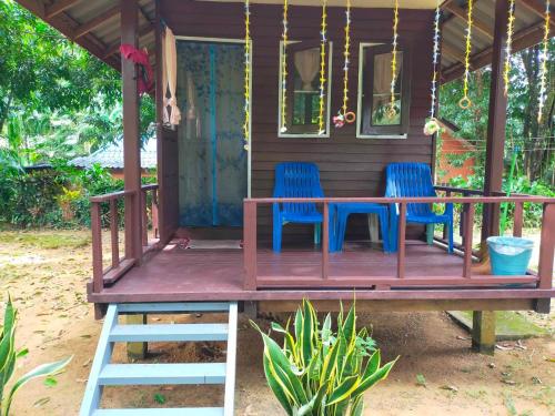 a house with two blue chairs and a table on the porch at Eco Bungalow in Ko Phayam