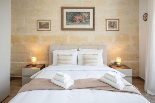 a bedroom with a white bed with towels on it at Exclusive Seafront Townhouse Sliema, Valletta view in Sliema