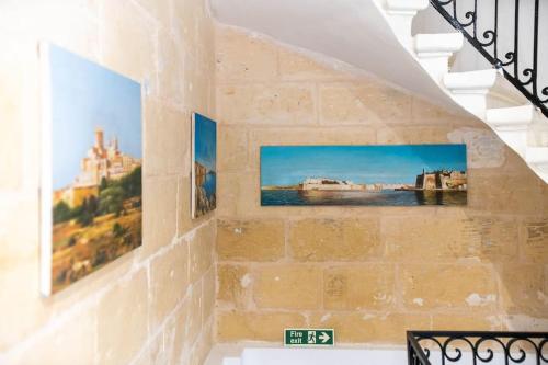 a staircase with two paintings on a brick wall at Exclusive Seafront Townhouse Sliema, Valletta view in Sliema