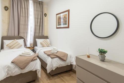 a bedroom with two twin beds and a mirror at Exclusive Seafront Townhouse Sliema, Valletta view in Sliema
