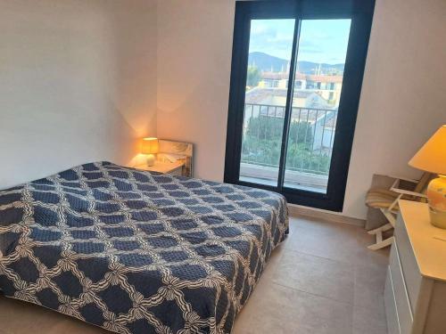 une chambre avec un lit et une grande fenêtre dans l'établissement Marcogdu- Proche de Saint-Tropez Appartement pour 4 personnes avec vue sur la marina, à Cogolin