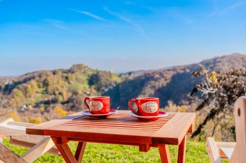 two red cups sitting on a wooden table with a view at Hilltop Panorama Chalet - Happy Rentals in Samobor