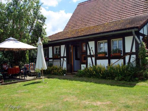a house with an umbrella and a table and an umbrella at Maison Fleurie in Schwabwiller