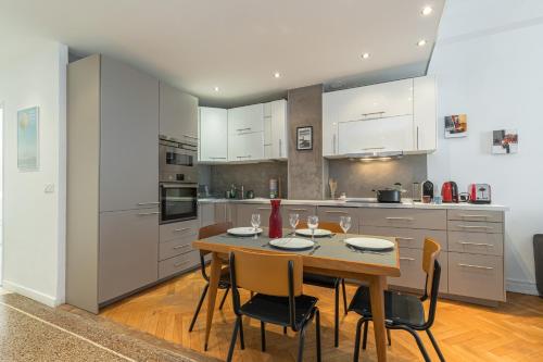 une cuisine avec une table et des chaises et une cuisine avec des armoires blanches dans l'établissement Charmant 3 Pieces 4 Pers WiFi AC, à Nice