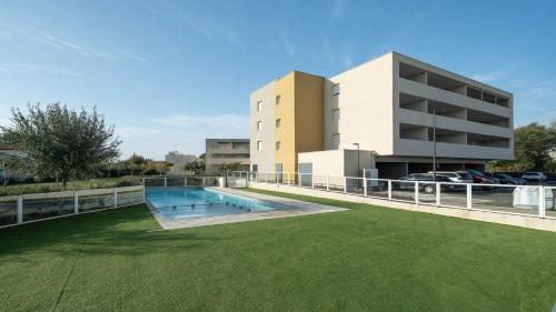 un immeuble avec une piscine devant un immeuble dans l'établissement La Dune 38 - Villa 3P6, à Valras-Plage