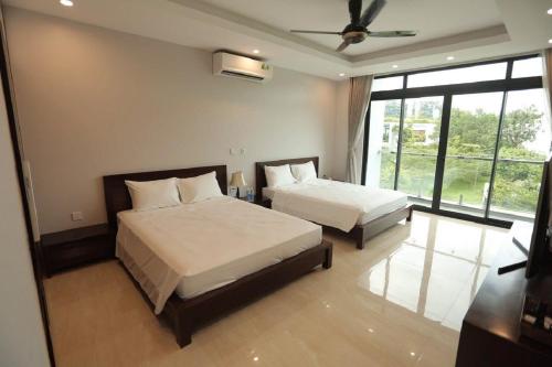 a bedroom with two beds and a ceiling fan at Flamigo Dai Lai Resort - Happy Villa in Ngọc Quang
