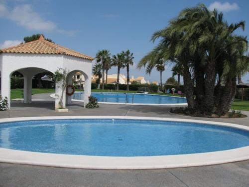 una grande piscina con gazebo e palme di Tranquila casa de vacaciones con terraza R139 by Novadesta a Gran Alacant