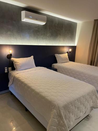 a bedroom with two beds with white sheets at Luster Hotel in João Câmara