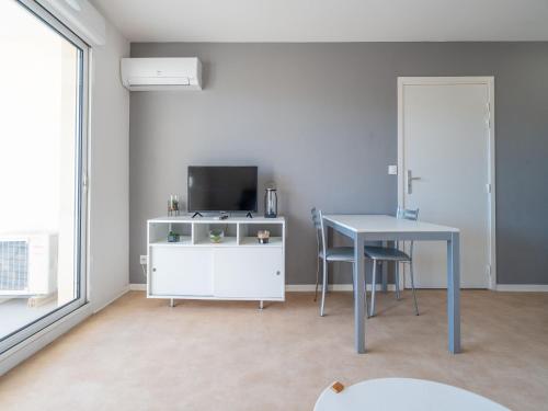 un salon avec une table et une télévision dans l'établissement La Dune B 203 - ST2, à Valras-Plage