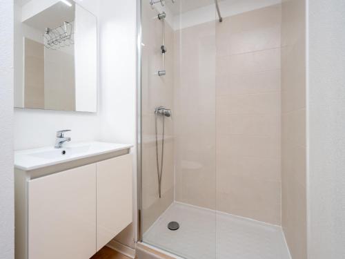 une salle de bain blanche avec une douche et un lavabo dans l'établissement La Dune B 203 - ST2, à Valras-Plage