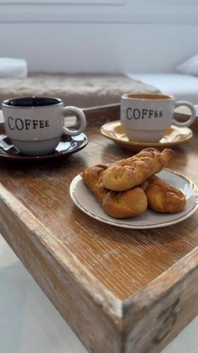 a table with two cups of coffee and plates of food at Mykonos Seaview Nests - Tourlos Getaways in Tourlos