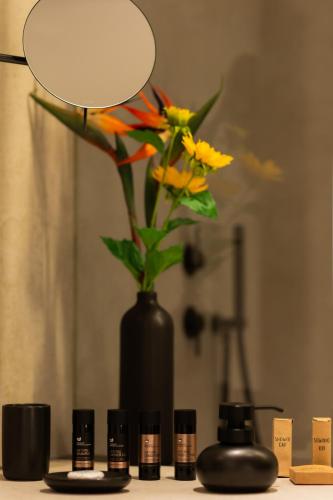 a black vase with flowers in it on a table at Maravilla Luxury Living in Kos Town