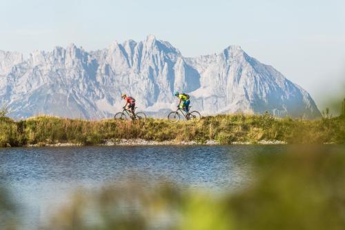 two people riding bikes next to a body of water at Appartement Alpenzauber in Kirchberg in Tirol