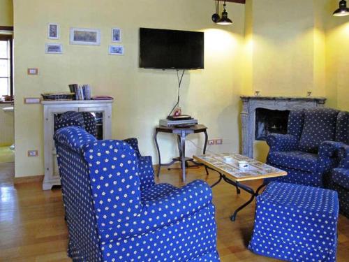 a living room with blue chairs and a table and a tv at Podere Caldaruccio La Pineta in Bosco