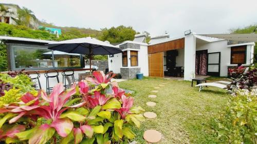 a house with an umbrella and some pink flowers at Villasjohnclair in Eau Vanée