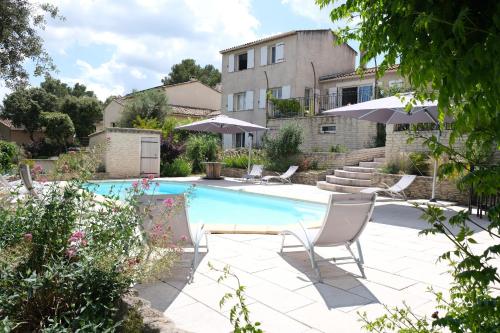a swimming pool with two chairs and an umbrella at Pleasant part of house with pool to share in Vaucluse, 4/6 people in Puget