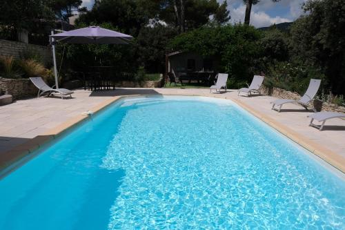 a swimming pool with chairs and an umbrella at Pleasant part of house with pool to share in Vaucluse, 4/6 people in Puget