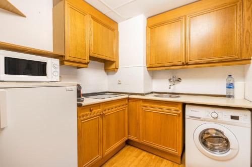 a kitchen with wooden cabinets and a washer and dryer at Mirador de la Neu in Pla de l'Ermita