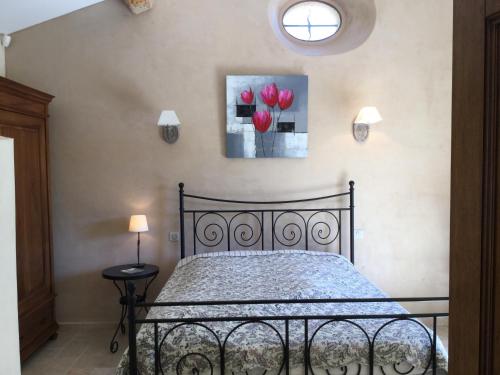 - une chambre avec un lit noir et des fleurs rouges sur le mur dans l'établissement typical provencal bastide, built of local stones, in the luberon in cheval-blanc with secured pool and wifi -sleeps 6 people., à Cheval-Blanc