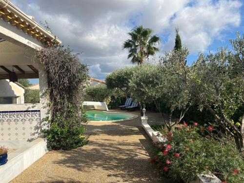 une arrière-cour avec une piscine, des arbres et une maison dans l'établissement Villa climatisée avec piscine privée 8 personnes proche des plages ménage offert, à Bessan