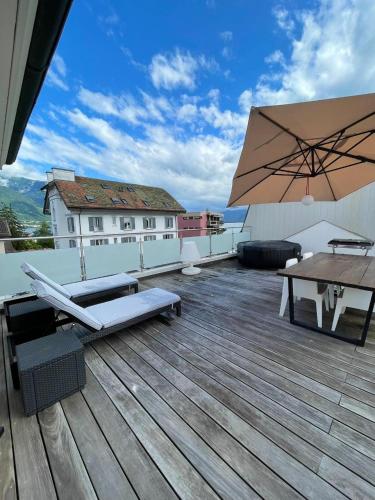 a wooden deck with a table and an umbrella at Appartement Montreux terrasse Lac in Montreux