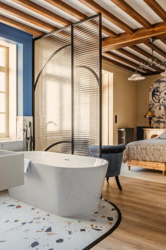 a large bathroom with a tub and a bed at Ma Tranquillite in Courpière