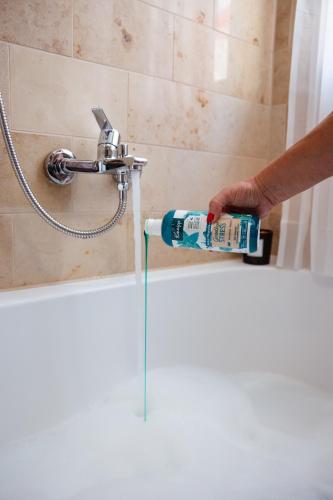 a person holding a bottle of toothpaste in front of a shower at Charmantes Haus -Nähe Parndorf-Neusiedl-Wien-HU-SK in Bruck an der Leitha