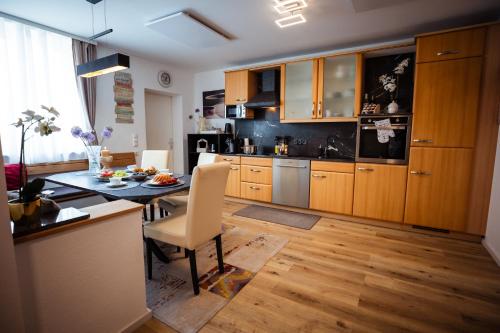 a kitchen with wooden cabinets and a table and a dining room at Charmantes Haus -Nähe Parndorf-Neusiedl-Wien-HU-SK in Bruck an der Leitha