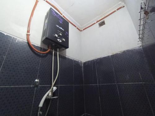 y baño con ducha y TV en la pared. en RedDoorz at Penginapan Hello Pacitan, en Pacitan