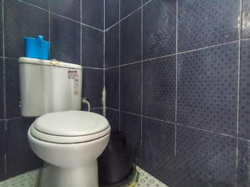 baño con aseo y pared de azulejos azules en RedDoorz at Penginapan Hello Pacitan, en Pacitan