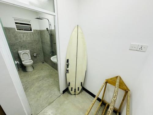 a bathroom with a surfboard next to a toilet at Coco Inn Polhena in Matara