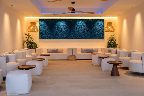 a room with white couches and tables and a painting at Royal Marina Suites Boutique Hotel - Adults Only in Puerto Calero