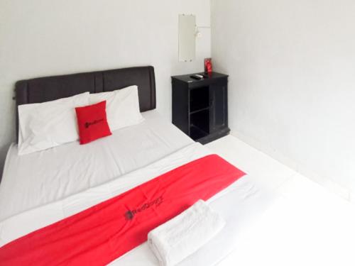 1 dormitorio con cama blanca y manta roja en RedDoorz at Penginapan Hello Pacitan, en Pacitan