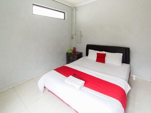 Un dormitorio con una gran cama blanca con almohadas rojas. en RedDoorz at Penginapan Hello Pacitan, en Pacitan