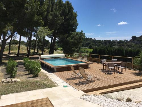 une terrasse avec une piscine, une table et des chaises dans l'établissement typical provencal farm in an exceptional natural site, the alpilles park - 8 people., à Les Fléchons