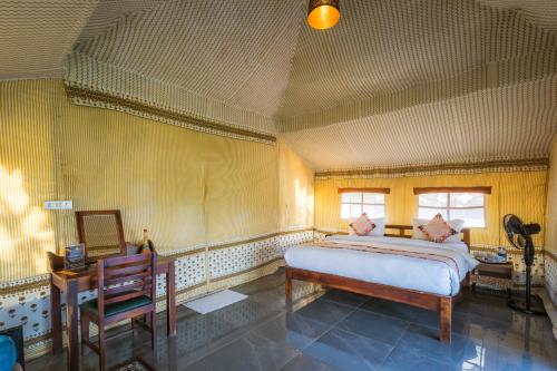 a bedroom with a bed and a table and a chair at RiverView Tent Resort in Kevadia
