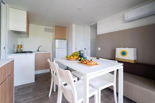 a kitchen with a white table with a bowl of fruit on it at Club del Sole Adriano Family Collection in Punta Marina