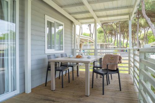 a porch with a table and chairs on it at Club del Sole Adriano Family Collection in Punta Marina