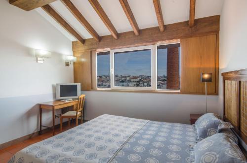 a bedroom with a bed and a desk with a computer at Hotel Principe Real in Lisbon