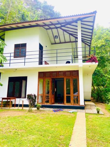 a white house with a balcony on top of it at Talalla Wonder View in Talalla South