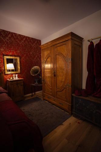 a bedroom with a large wooden cabinet and red wallpaper at Charmantes Haus -Nähe Parndorf-Neusiedl-Wien-HU-SK in Bruck an der Leitha
