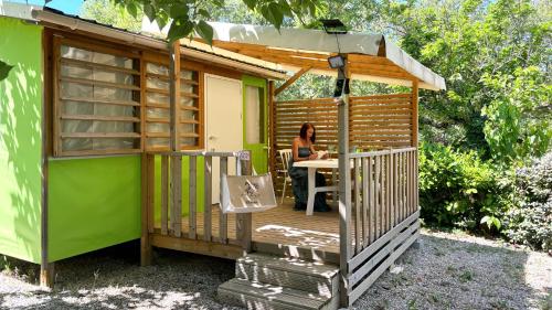a woman sitting at a table in a wooden house at Camping Le Saint Clair in Moustiers-Sainte-Marie