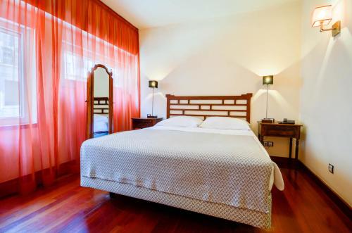 a bedroom with a large bed with red walls at Hotel Principe Real in Lisbon