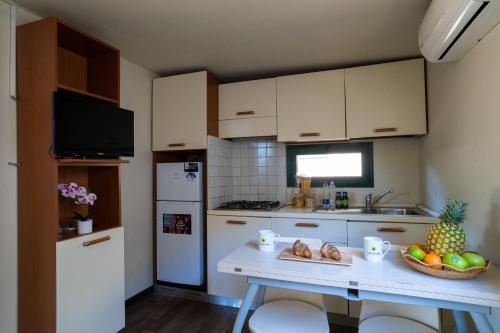 a kitchen with a table with a bowl of fruit on it at Club del Sole Adriano Family Collection in Punta Marina