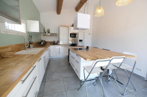 a kitchen with white cabinets and a wooden counter top at beautiful provencal mas with pool in barbentane, close to avignon, sleeps 8. in Barbentane