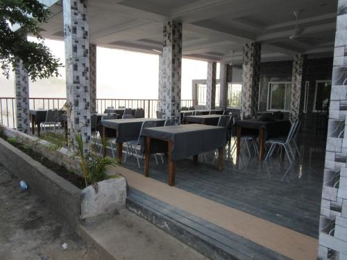 a restaurant with tables and chairs on a deck at Island Hotel Janjanbureh in Georgetown