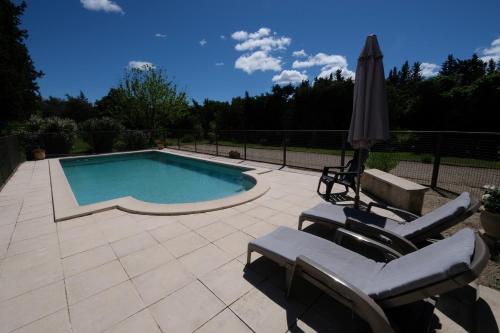 une piscine avec deux chaises et un parasol dans l'établissement mas attached to another building with private pool 4 people in carpentras, at the foot of the ventoux in provence., à Carpentras