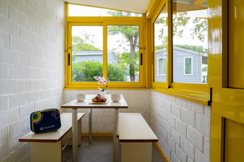 a small table with two chairs and a window at Club del Sole Adriano Family Collection in Punta Marina