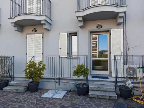 a white house with potted plants on the steps at CasaOlivier appartamento con giardino e biciclette in Crema